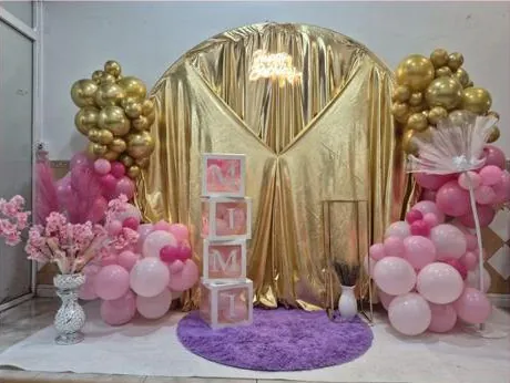 Cortina dorada con globos rosas y dorados y alfombra lila