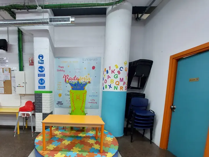 Mesa infantil sobre plataforma de puzle junto al cartel de Badafesta, Sala 1