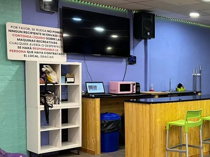 Barra de bar con taburetes verdes, microondas y tele